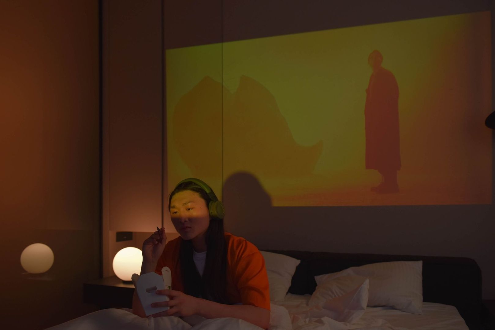 Person mit Kopfhörern schaut im abgedunkelten Schlafzimmer einen Film
