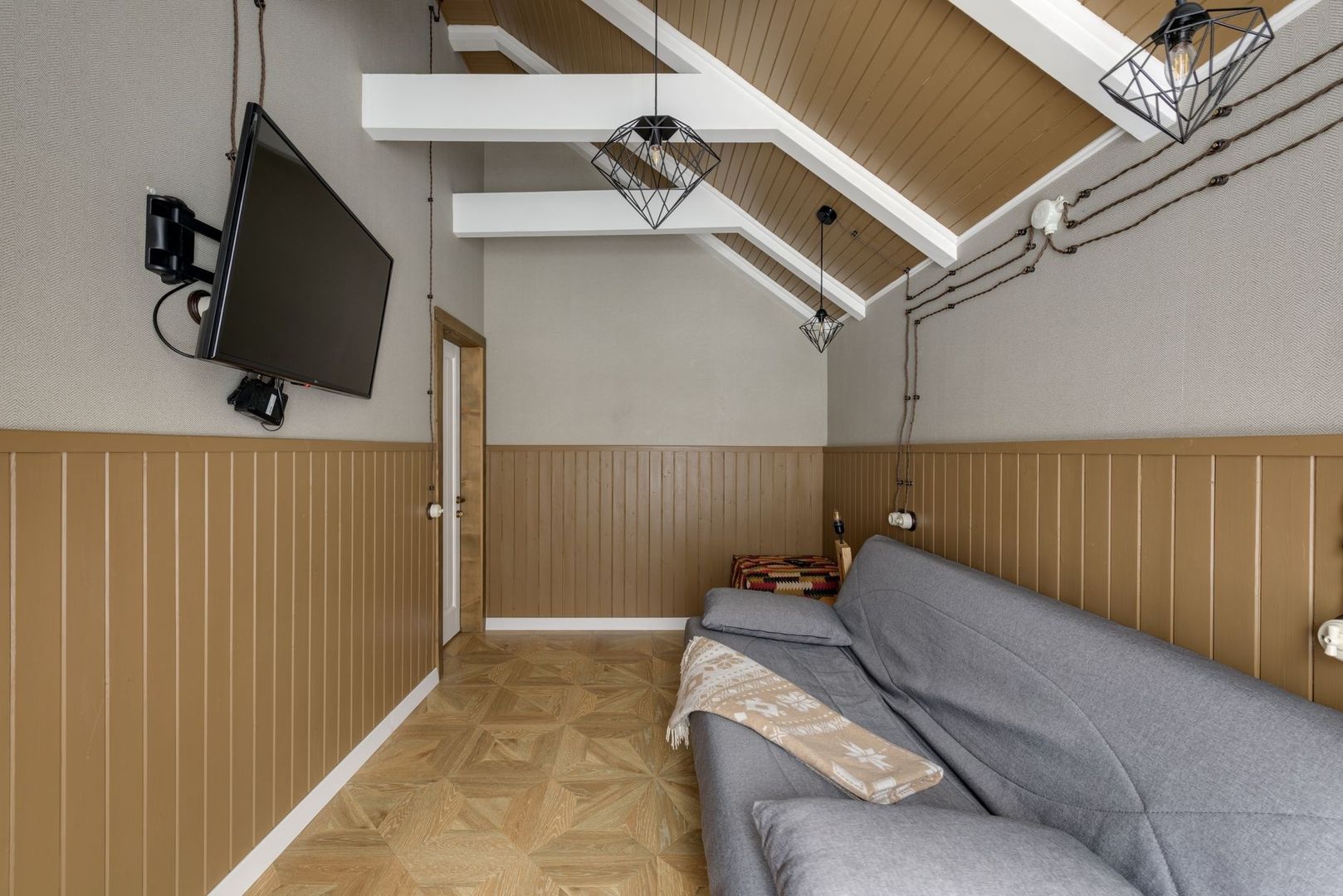 Wohnzimmer mit Fernseher, grauem Sofa und dekorativer Beleuchtung